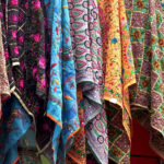 An image of the bustling market with pashmina scarves on display at a store.