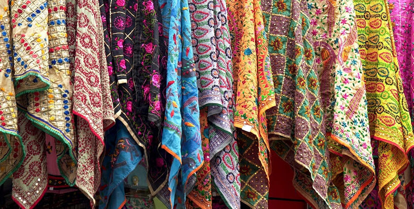 An image of the bustling market with pashmina scarves on display at a store.