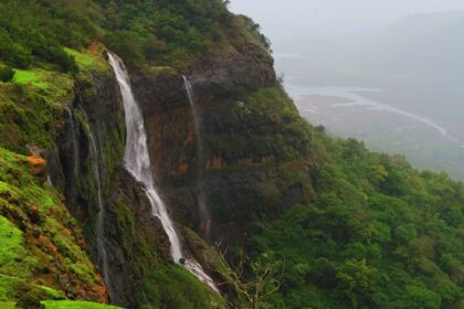 A beautiful waterfall cascading down rocky terrain surrounded by greenery in Matheran.