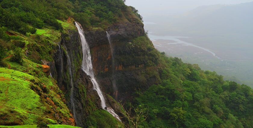 A beautiful waterfall cascading down rocky terrain surrounded by greenery in Matheran.