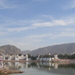 A serene view of Pushkar Lake in India, surrounded by whitewashed buildings and temples.