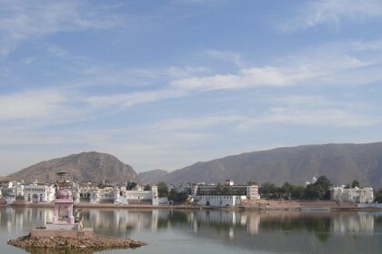 A serene view of Pushkar Lake in India, surrounded by whitewashed buildings and temples.