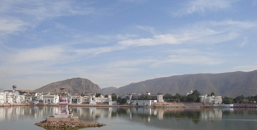 A serene view of Pushkar Lake in India, surrounded by whitewashed buildings and temples.