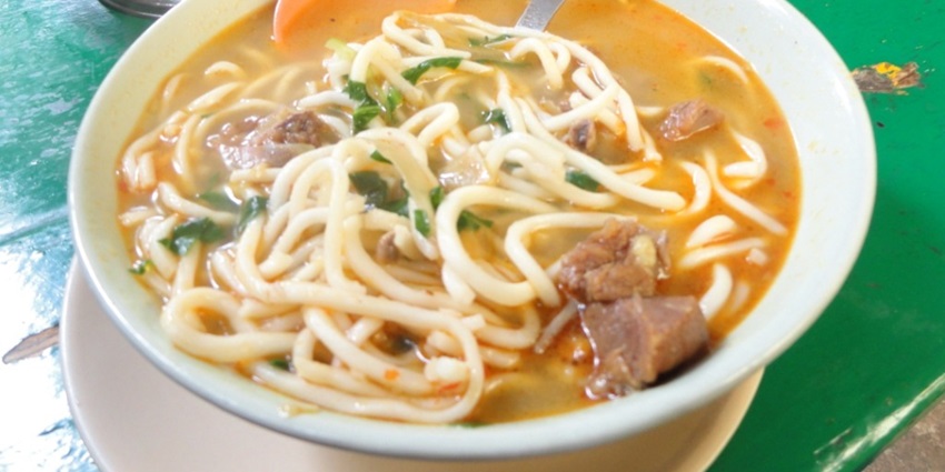 Traditional Himachali Thukpa, noodles with hot soup served on a plate with fresh vegetables