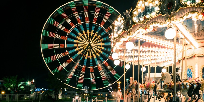 An image showing a night view of a carnival with decorative lights and horses.