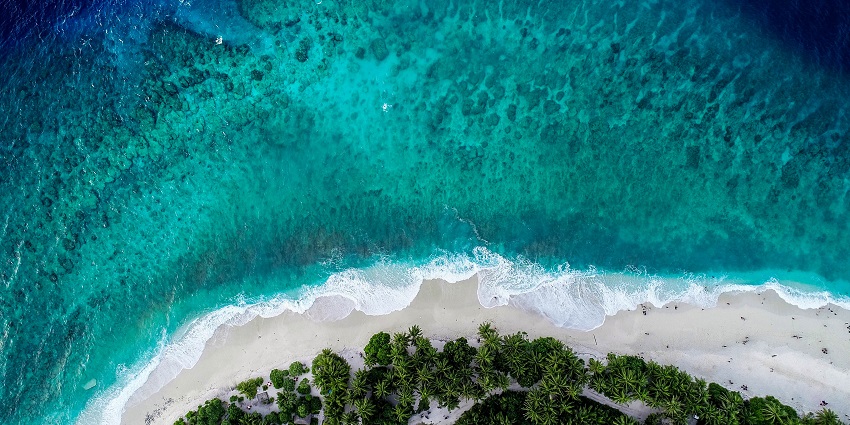 Aerial view of the turquoise waters crashing the sandy shores of the beach