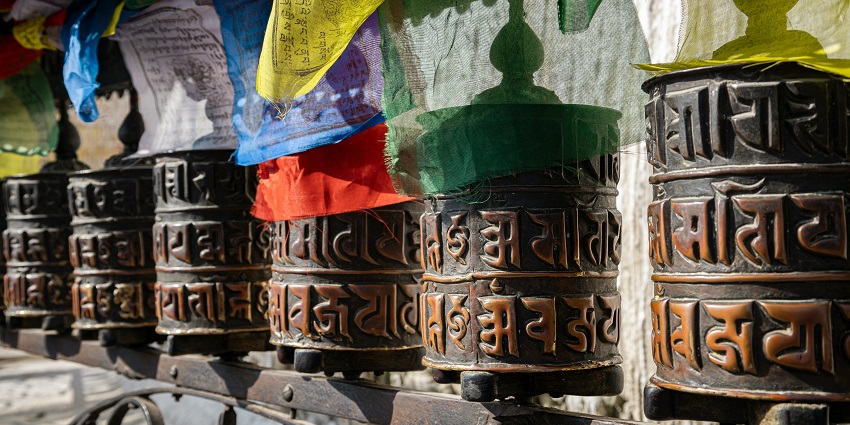 Row of bells hanging from a building with a clear blue sky in the background