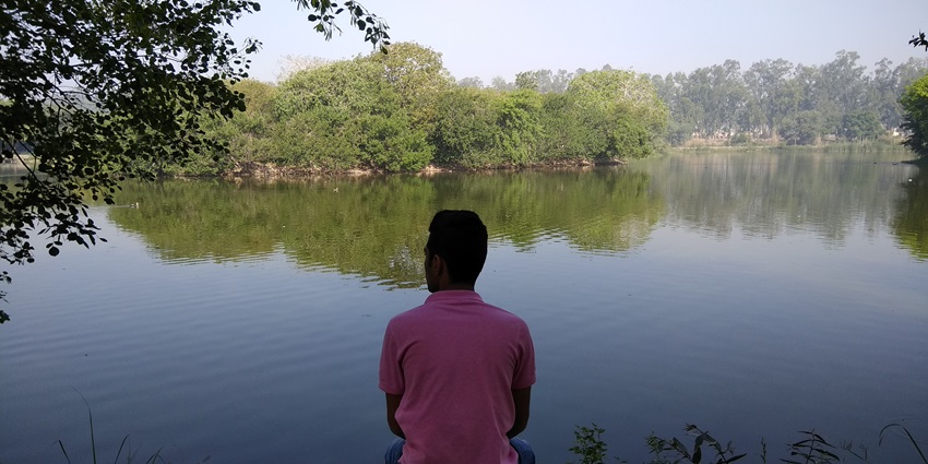 Picturesque view of Tilyar Lake surrounded by lush greenery under clear blue sky