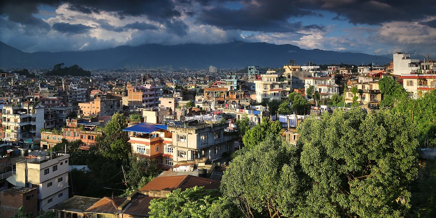 Kathmandu street scene during monsoon with lush greenery and wet roads.