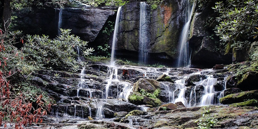 Close-up of Ghagra Waterfalls splashing over rocks with green trees around it.