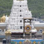 A picture of a temple taken from a distance with a tall white building in the middle of the compound