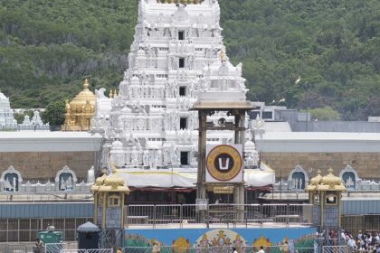 A picture of a temple taken from a distance with a tall white building in the middle of the compound