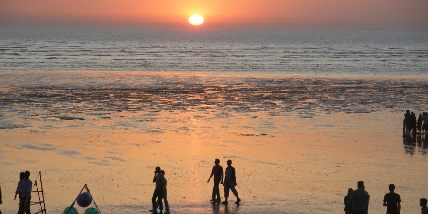 Picturesque view of Tithal beach sunset in orange colour and people exploring the beach