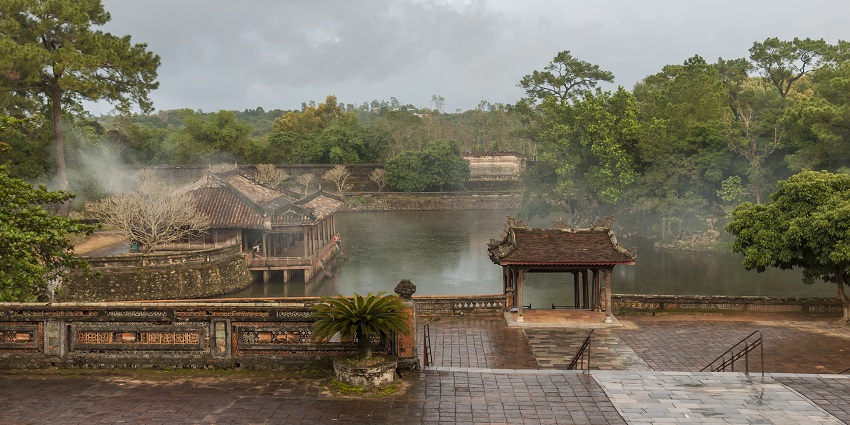 A glimpse of the iconic Tomb Of Emperor Tu Duc surrounded by azure waters and trees.