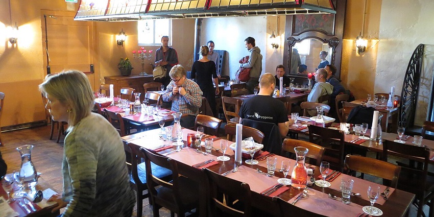 A picture of a cafe with people sitting at the tables to have dinner and drinks
