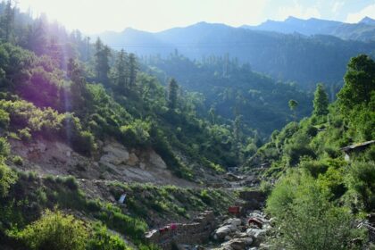 A scenic view of Tosh village in Himachal Pradesh with distant mountains.