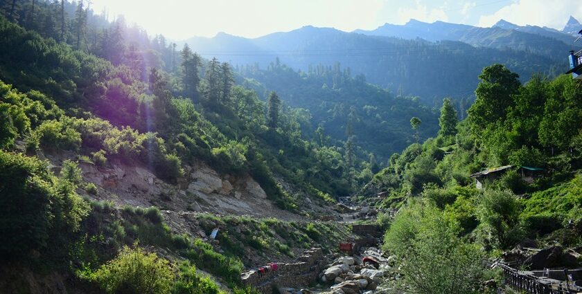 A scenic view of Tosh village in Himachal Pradesh with distant mountains.