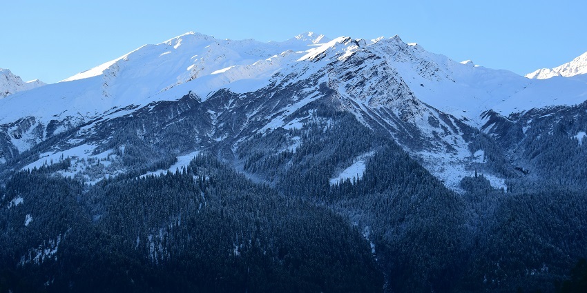 A breathtaking vista of snow-capped peaks at Tosh Village, a hotspot in Himachal Pradesh.