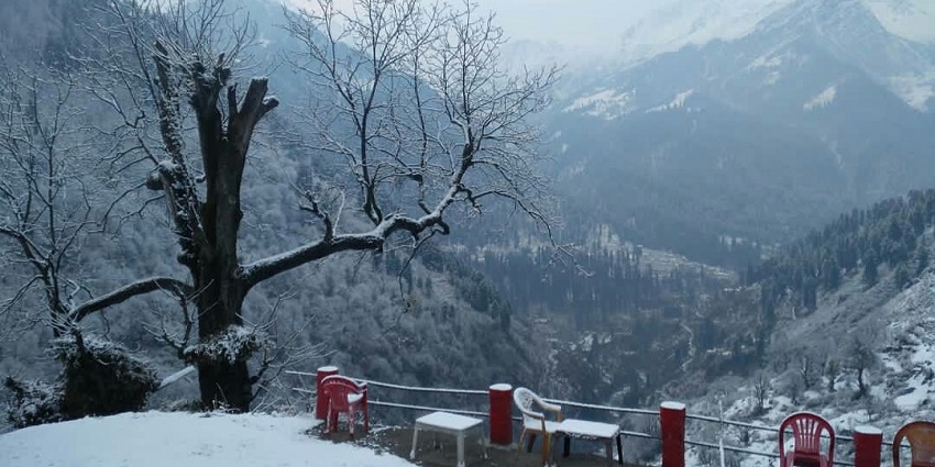 A picture of a hilltop covered in snow with benches and chairs kept for visitors to enjoy the views