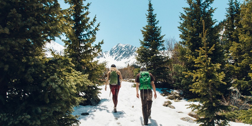 A breathtaking view of a two people trekking up hills with mountains in the background.