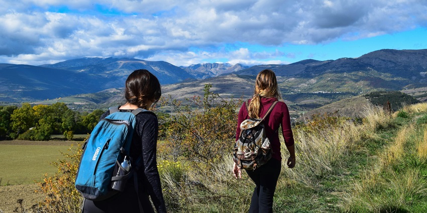 Travellers trekking through the lush green valleys with twisty roads and rocks around