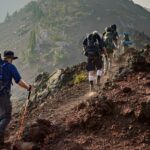 A fascinating view of a group of people hiking up rocky hills during the daytime.