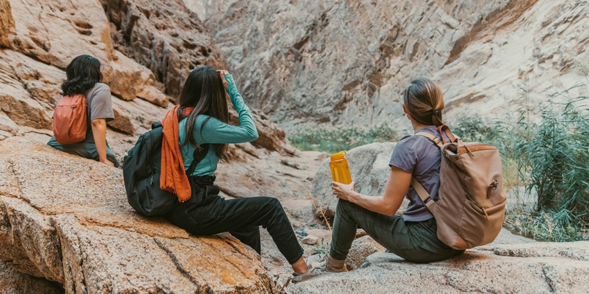 A group of friends sitting on a large rock, enjoying nature and each other's company.