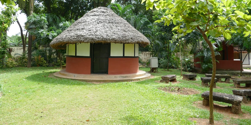 Image of a tribal hut on the grounds of the Tribal Museum - surrounded by lush greenery