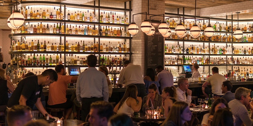 Group of people gathered inside a lively bar with warm lighting and a casual atmosphere