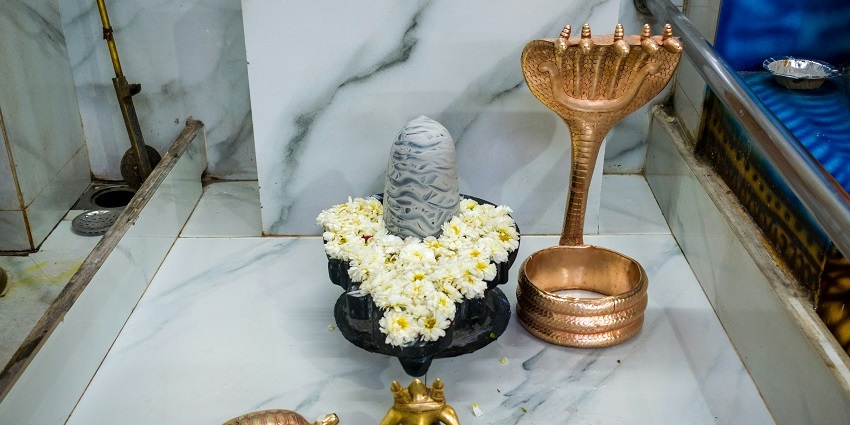 An inside view of the Tribeniswar Temple featuring shivalinga decorated with garlands.
