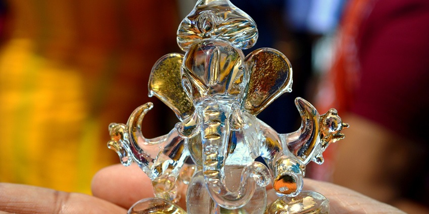 A close-up of a decorative Ganesh figurine made of glass, featuring intricate details.