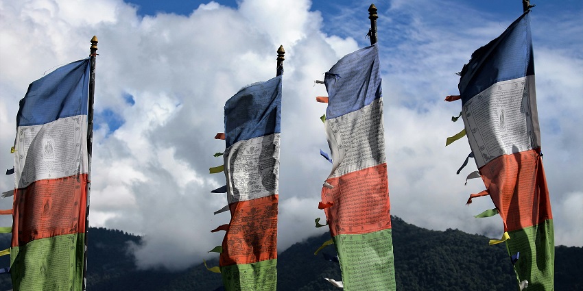 The aerial view flying Buddha flags in Trongsa Dzong with green trees and mountains