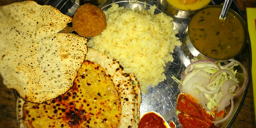 A plate of Dal Baati Churma, Laal Maas, and traditional Rajasthani sweets, one of the best things to do in Ajmer.