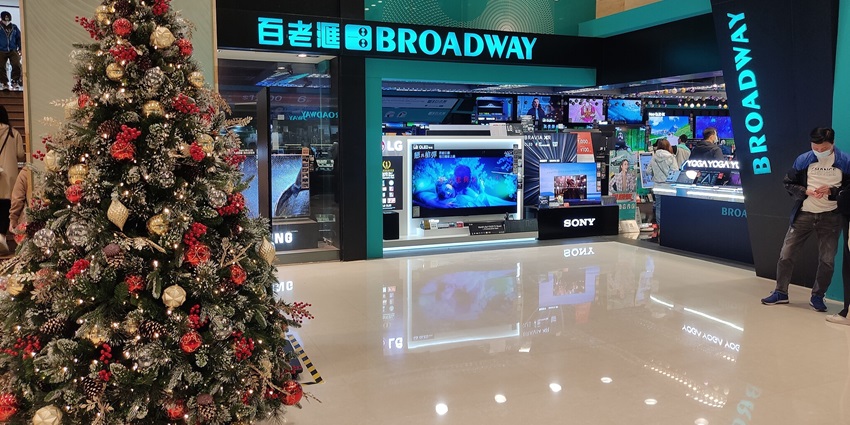 Christmas tree inside a mall with a shop and man on the side for buying electronic goods.