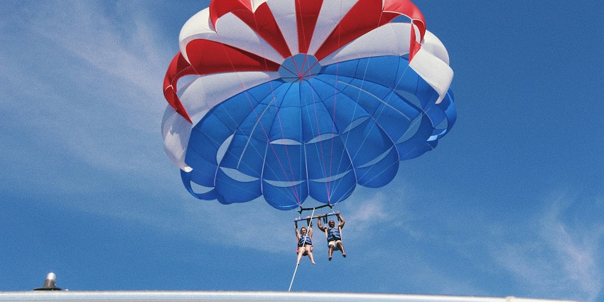 A breathtaking view of two people attached to a parachute enjoying during the day.