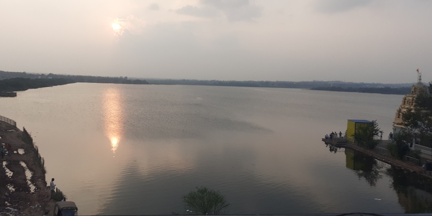 The placid lake with a temple surrounded by lush greenery.