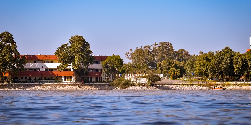 Panoramic view of the Karna lake aligned with lush trees at its shore