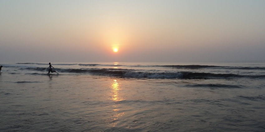 A picture of a quaint sunrise along the shore of a scenic beach with orange hues all around