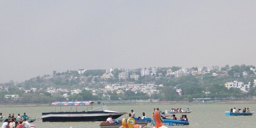Tourists boating at Upper Lake in Bhopal, showcasing the expansive water body surrounded by greenery and urban areas