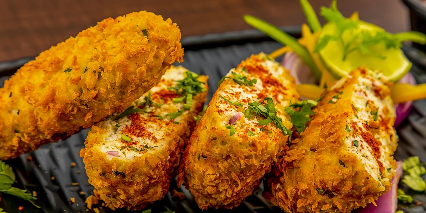 A glimpse of fried chicken served on a plate garnished with coriander leaves and lime.