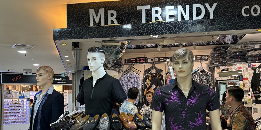 A view of a fashion shop with three mannequins, shoes, and clothing displayed for sale.