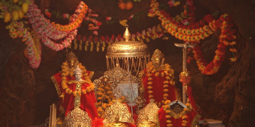 Inside a beautifully decorated Vaishno Devi Temple with idols adorning flower garlands.