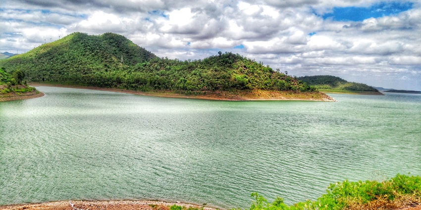 The lake reflects a majestic mountain in the background, surrounded by leafy vegetation