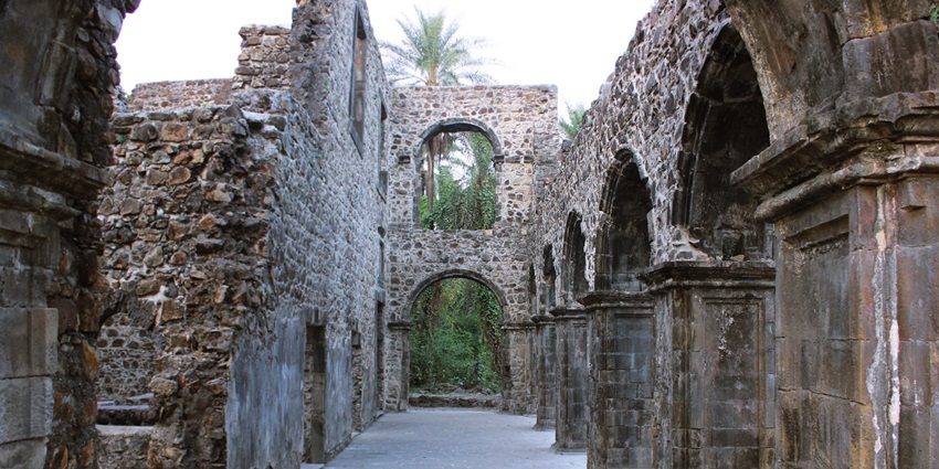 Ruins of Vasai Fort with arched doorway and stone walls under clear sky.