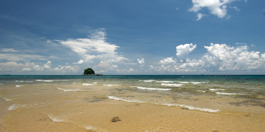 A stunning view of Tioman Island's lush greenery and clear blue waters under a bright sky.