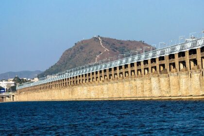 A picture of a bridge crossing a river with boats sailing in the river and a hill in the background