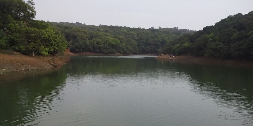 A serene view of Charlotte Lake in Matheran, Maharashtra, surrounded by lush green hills.