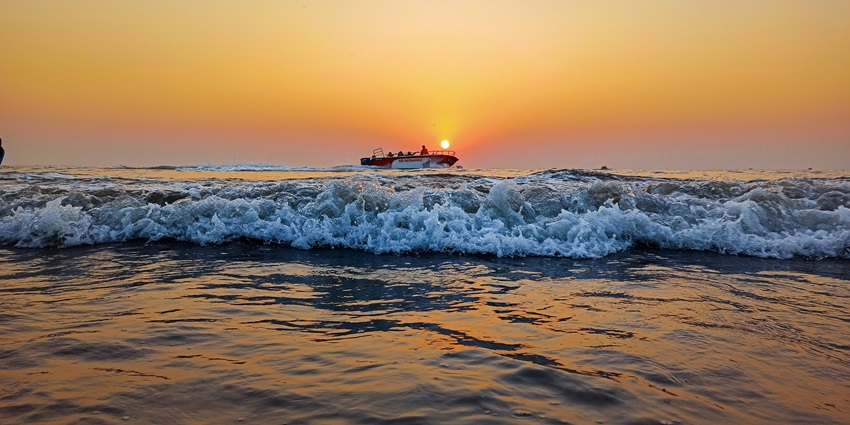 People strolling along Juhu Beach, Mumbai, with Arabian Sea's waves on the sandy shore.