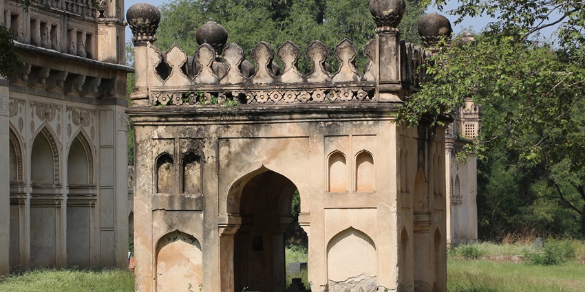 Stone mausoleum with pointed arches and domed roof in Qutb Shahi Tomb complex