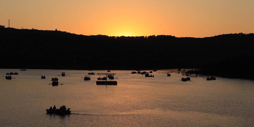 A view of Venna Lake in Mahabaleshwar, surrounded by hills under a clear sky.